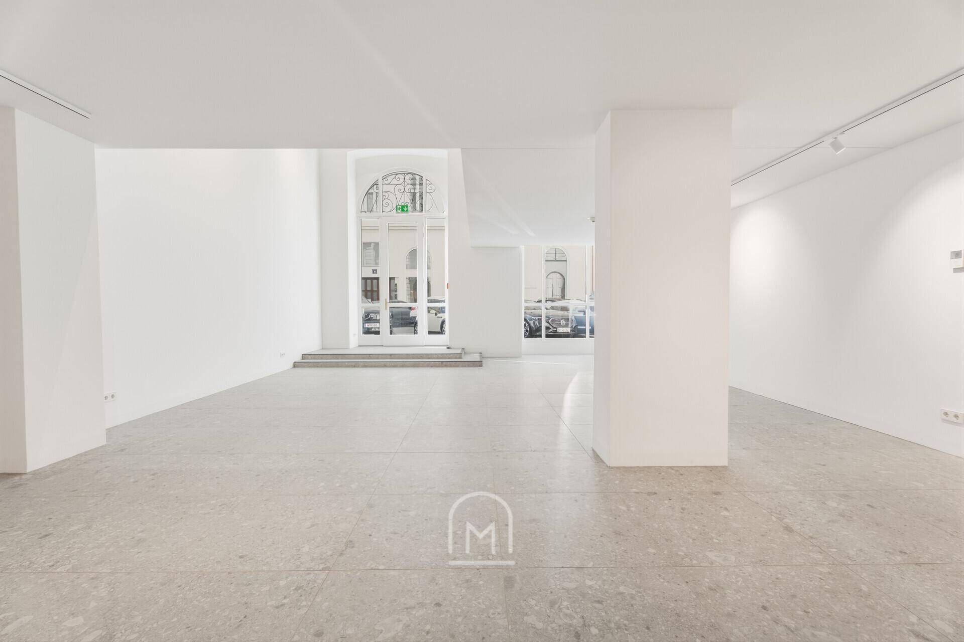 Weitläufiger, heller Gewerberaum mit minimalistischem Design und direktem Zugang zur Straße.