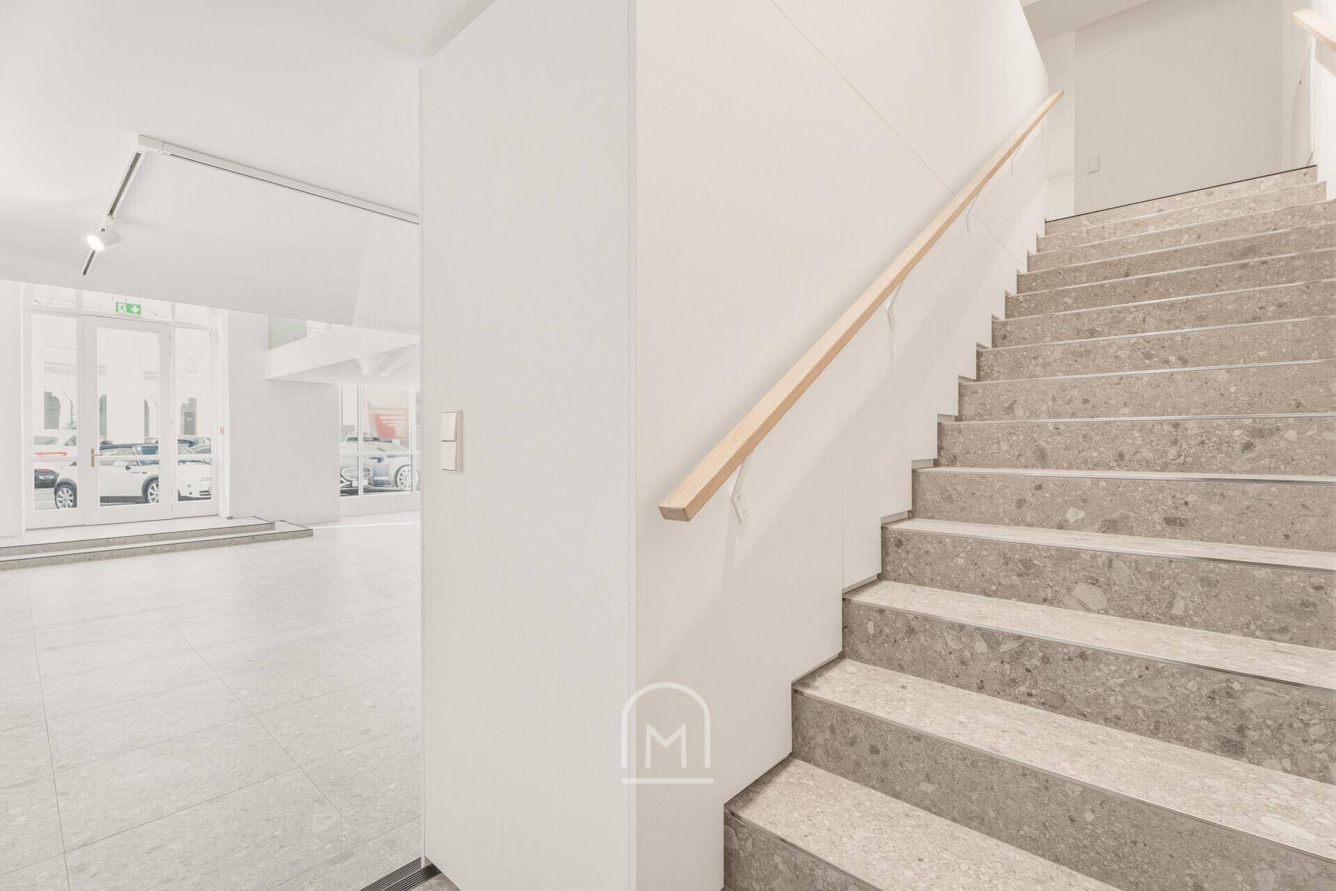 Elegante Steintreppe mit Holzhandlauf, die zur Galerieebene führt.