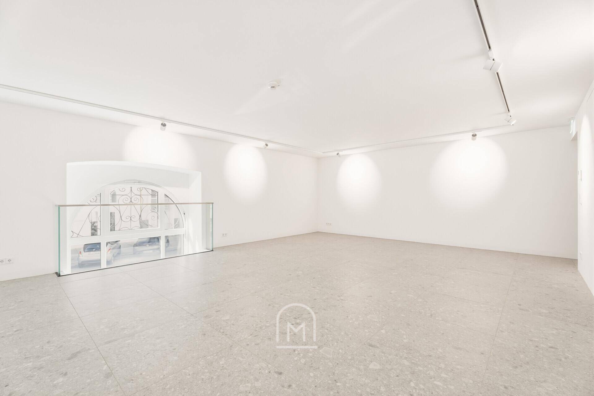 Helle Galerieebene mit elegantem Bogenfenster und moderner Glasabtrennung.
