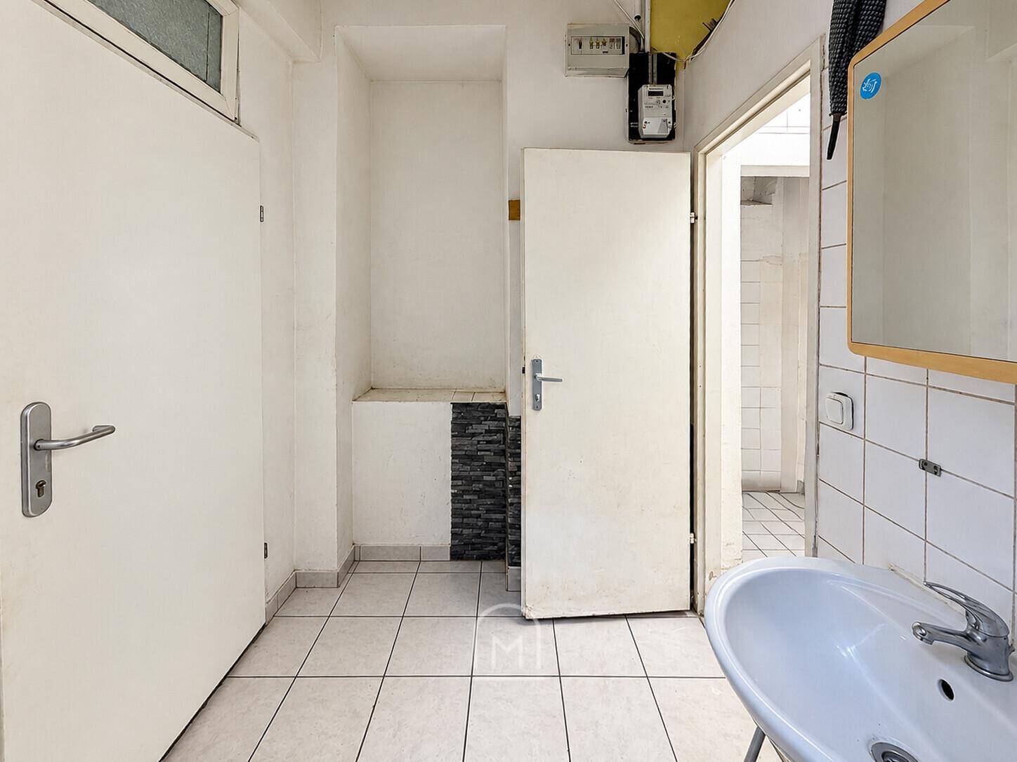 Kleines Badezimmer mit Waschbecken, Spiegelschrank und Fliesenboden.