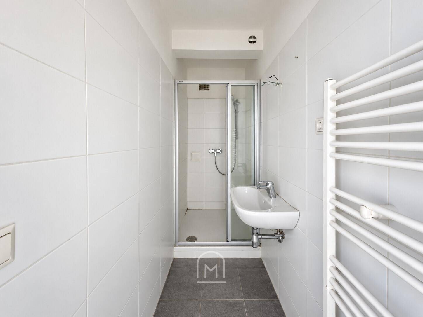 Modernes Badezimmer mit Duschkabine, Waschbecken und beheiztem Handtuchhalter.