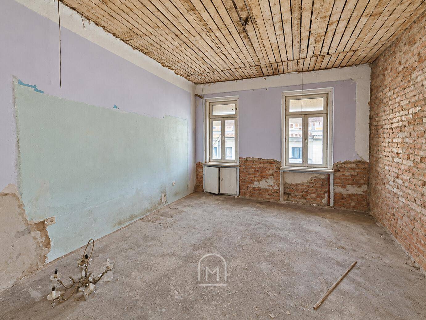 Renovierungsbedürftiger Raum mit freigelegten Wänden und Deckenbalken, bietet viel Potenzial.