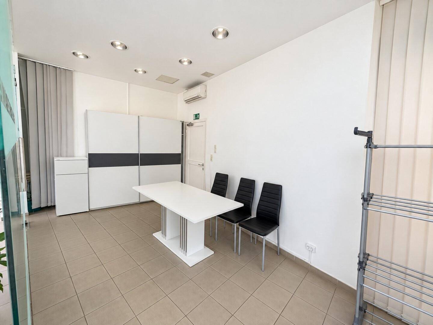 Heller Büroraum mit modernem Tisch, Stühlen und großem Schiebetürenschrank.