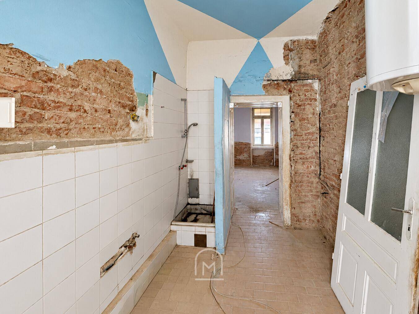 Badezimmer im Sanierungszustand mit Fliesen und freigelegten Ziegelwänden, bereit für Modernisierung.