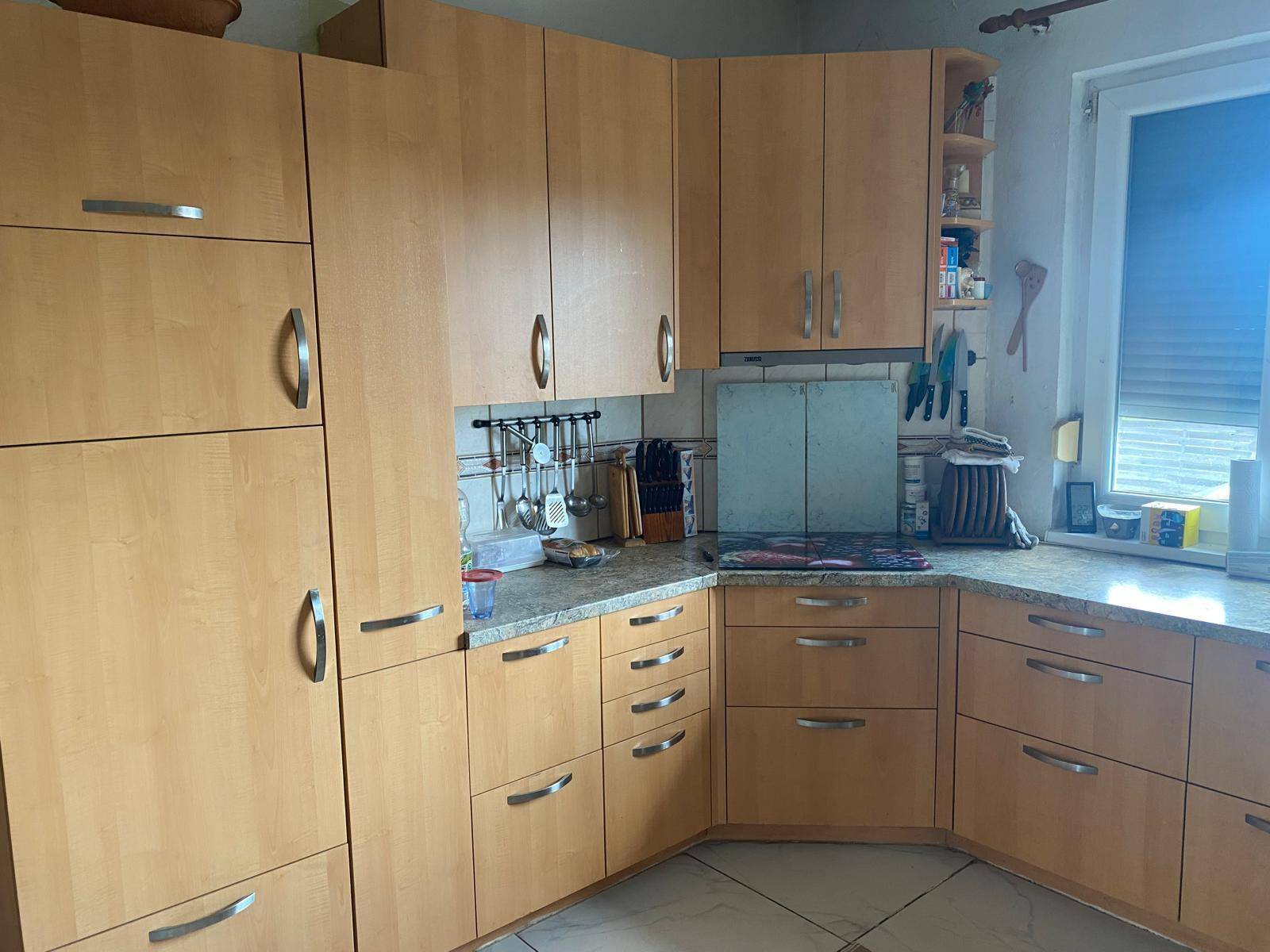 Funktionale Küche mit hellen Holzschränken, Granitarbeitsplatte und Fenster.