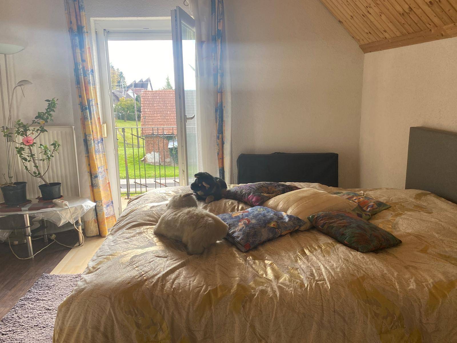 Schlafzimmer mit Doppelbett, Holzdachschräge und Zugang zu einem Außenbereich.