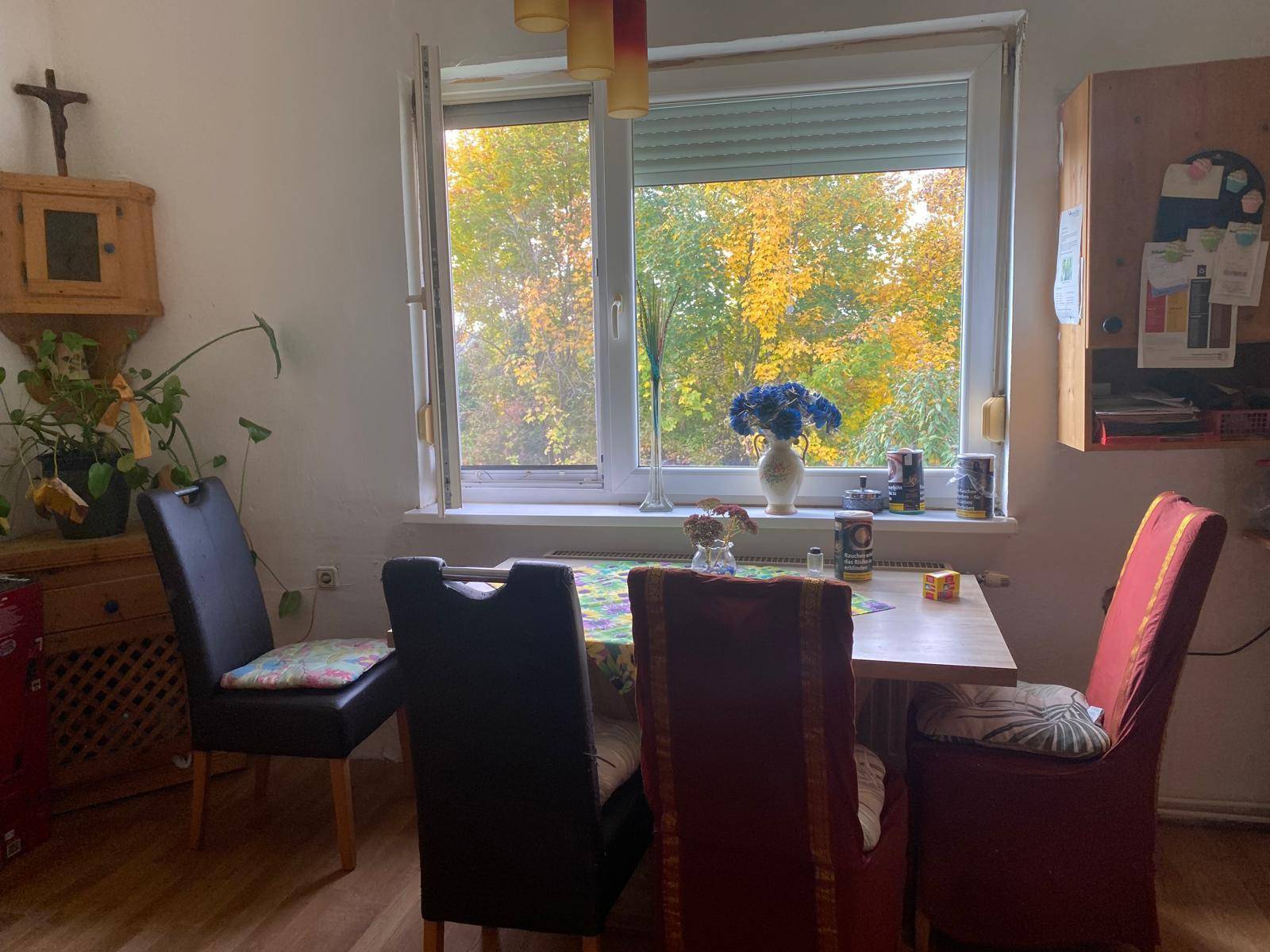 Heller Essbereich mit Esstisch, Stühlen und Blick auf herbstliche Bäume.