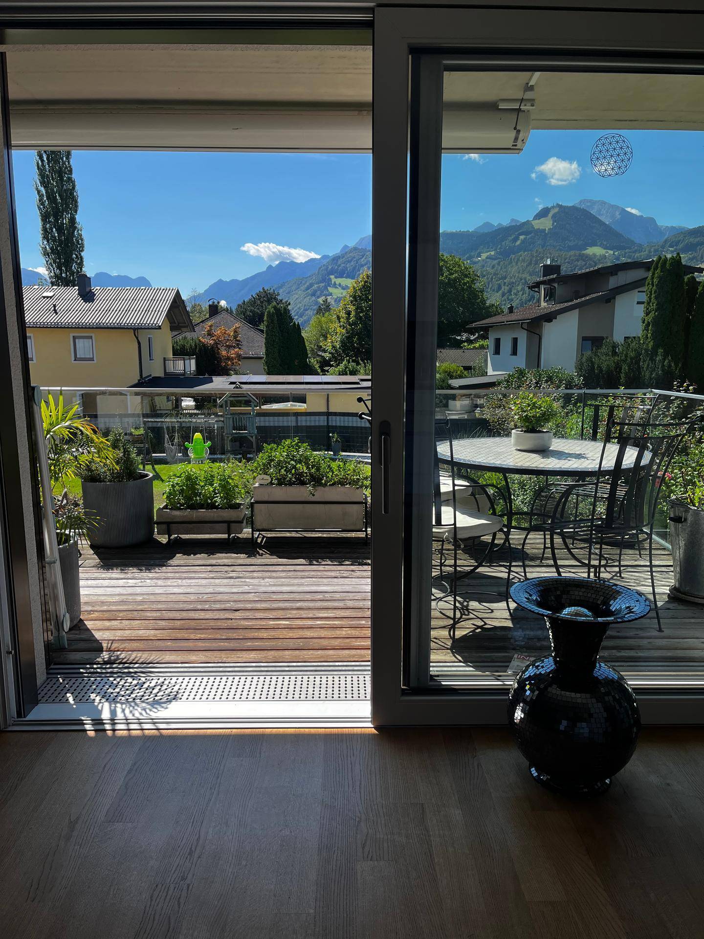Große Holzterrasse mit Gartenmöbeln und einem beeindruckenden Blick auf die Berge.