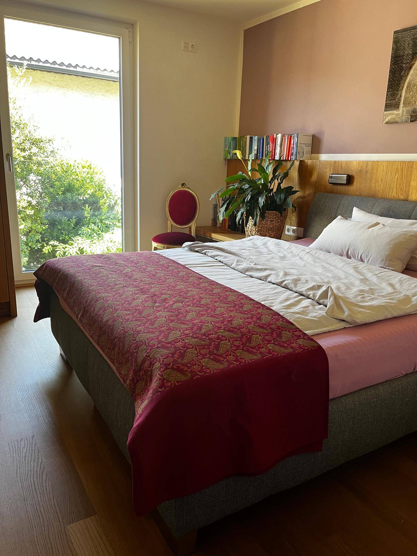 Helles Schlafzimmer mit Holzboden, großem Bett und Zugang zu einem Außenbereich.