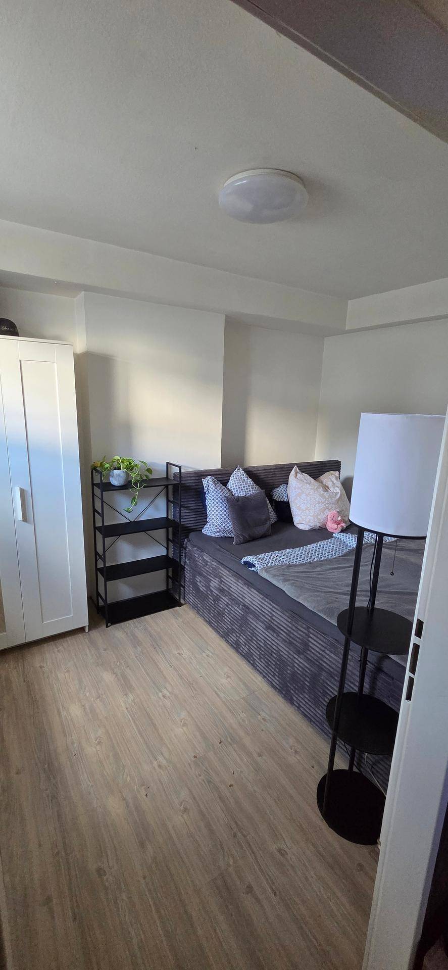 Gemütliches Schlafzimmer mit Bett, Kleiderschrank und Laminatboden.