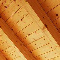 Detailaufnahme einer schrägen Holzdecke mit sichtbaren Holzbalken und Holzverkleidung.