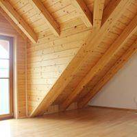 Raum mit schräger Holzdecke, Holzwänden und hellem Holzboden, durchflutet von Tageslicht.