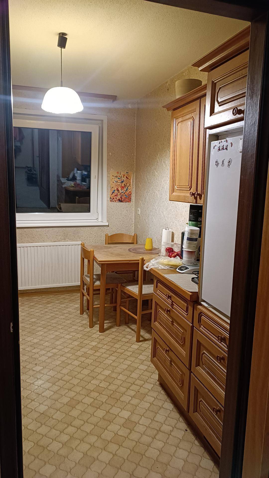 Gemütliche Küche mit traditionellen Holzschränken, Essbereich und einem Fenster für natürliches Licht.