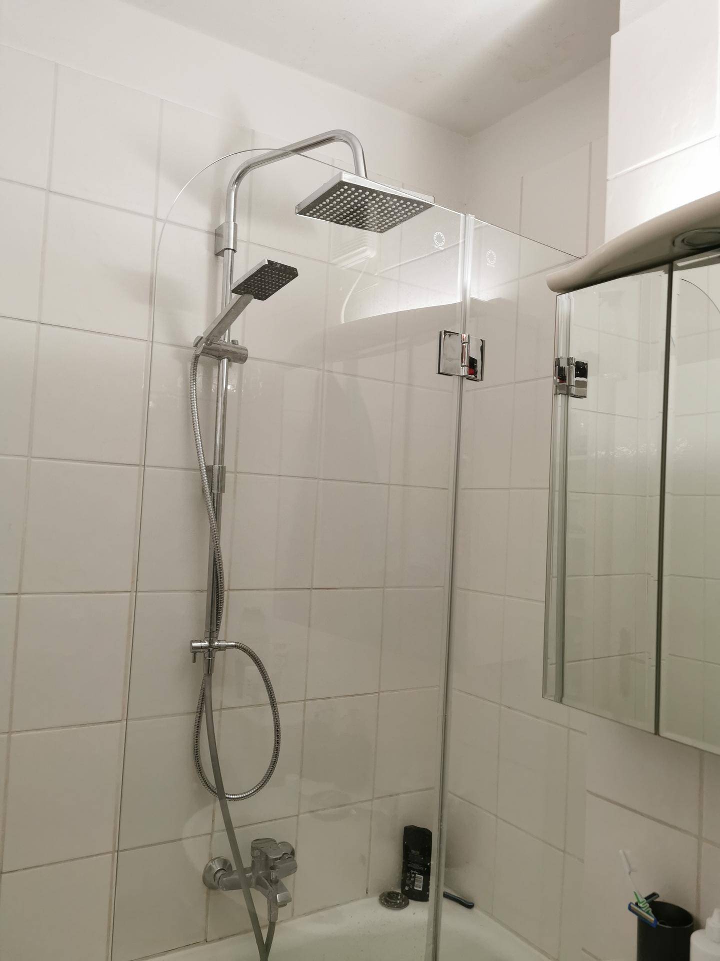 Modernes Badezimmer mit Badewanne, Duschabtrennung und Regendusche, komplett gefliest.
