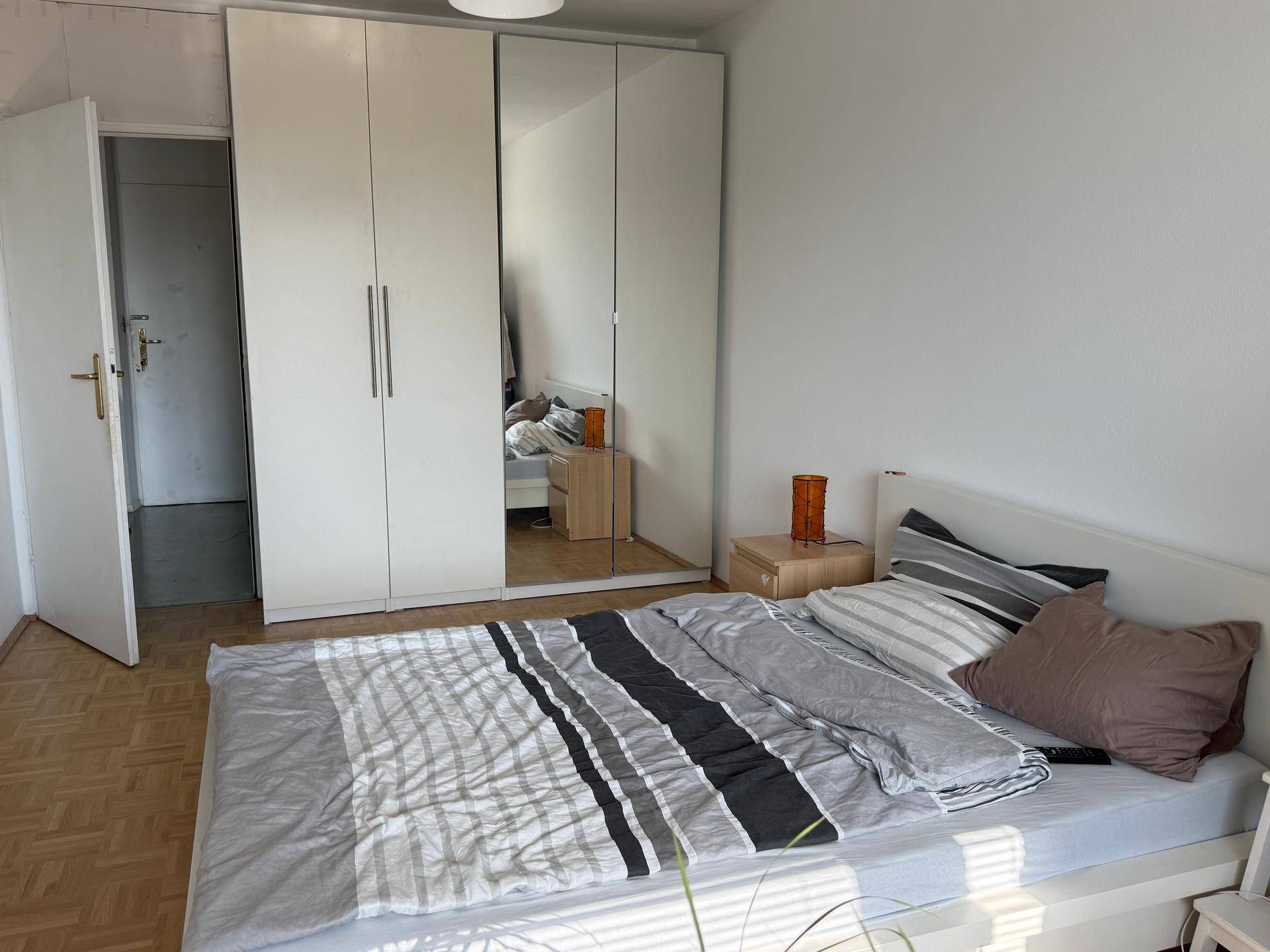 Schlafzimmer mit Bett, Nachttisch und großem Spiegelschrank, bietet viel Stauraum.