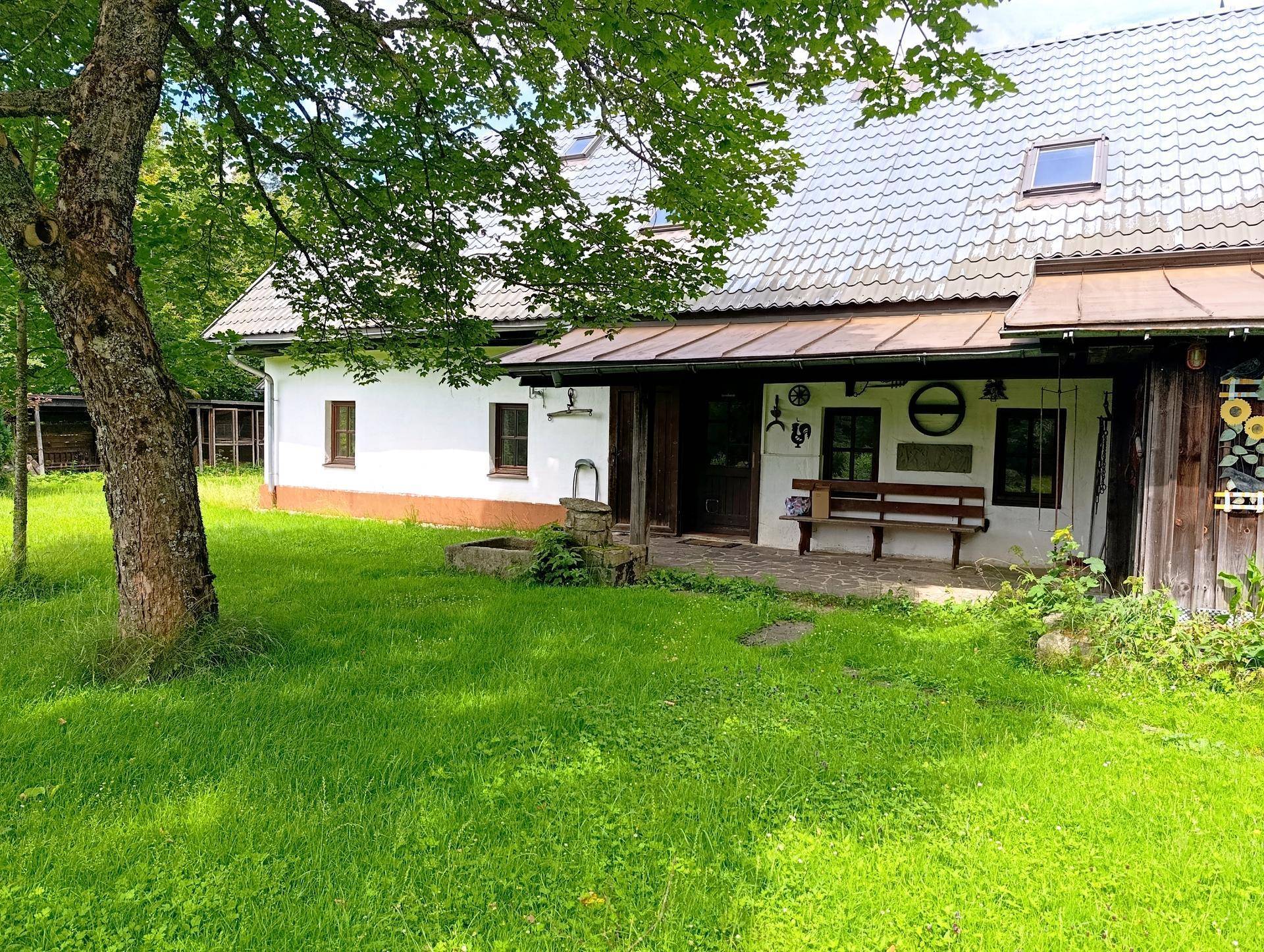 Charmantes Landhaus mit weißer Fassade, Holzelementen und einem gepflegten Vorgarten.