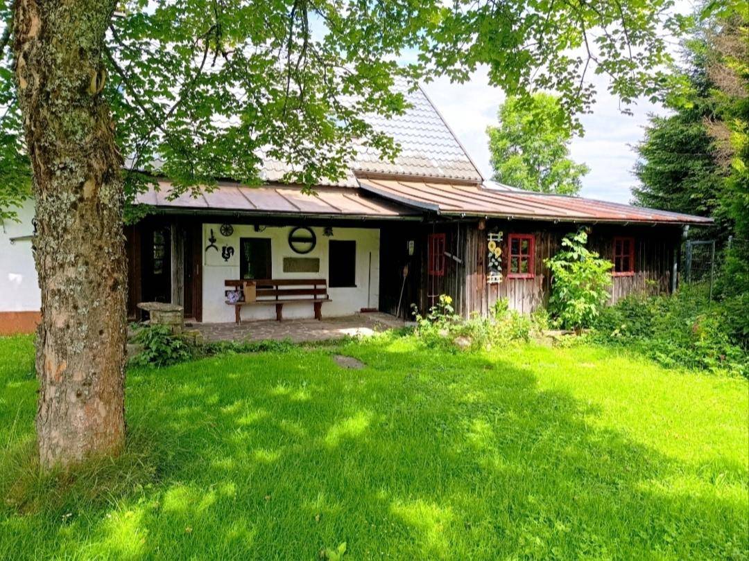 Traditionelles Landhaus mit weißer Fassade, Holzelementen und einem gepflegten Vorgarten.