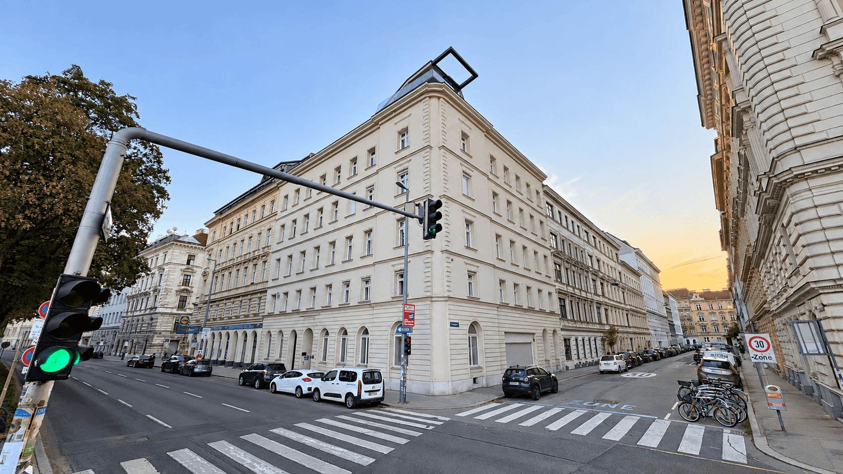 Großes Eckgebäude in städtischer Umgebung mit klassischer Architektur und belebter Straße.