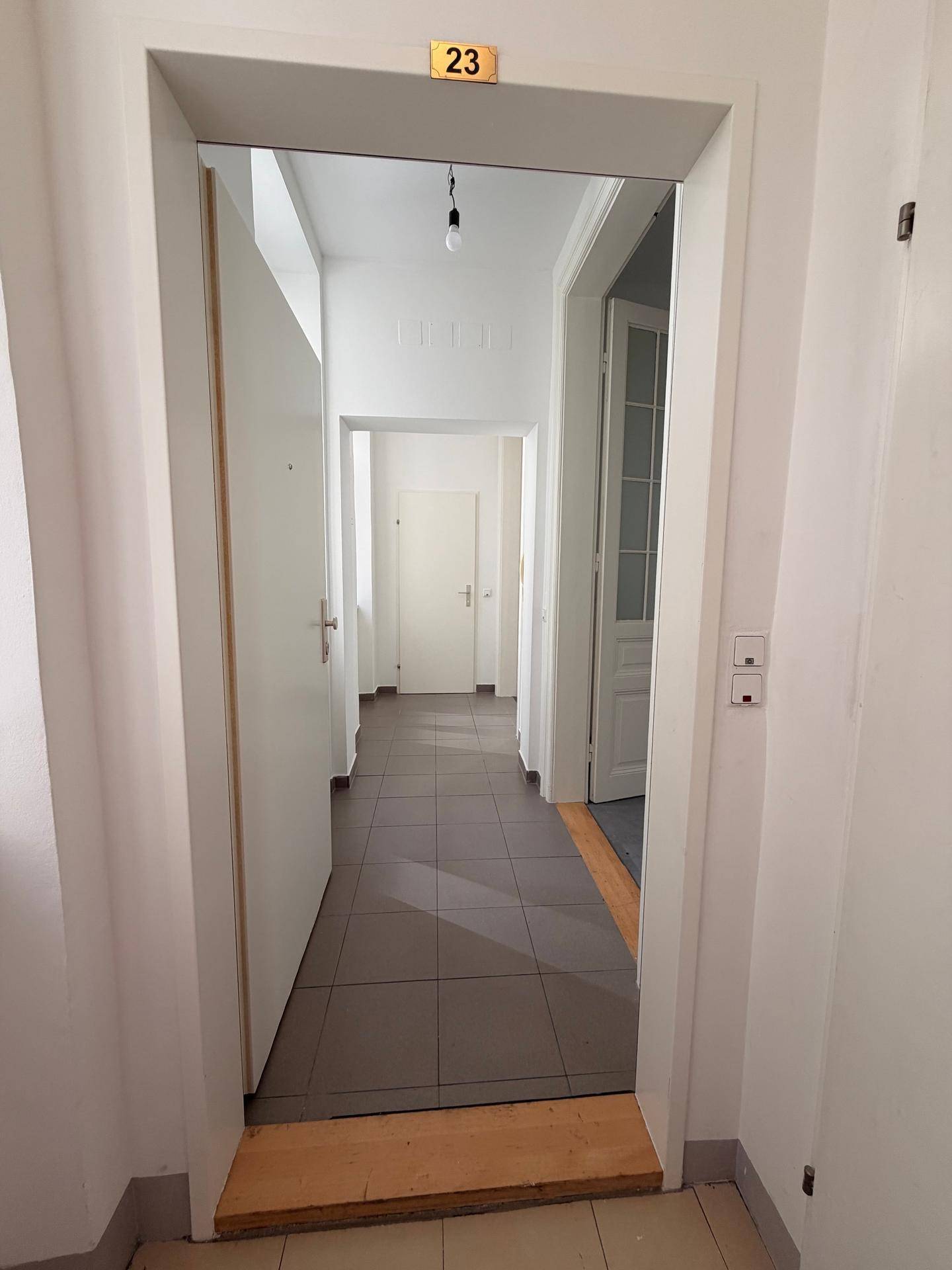 Eingangsbereich eines hellen Flurs mit Fliesenboden, der zu den verschiedenen Zimmern der Wohnung führt.