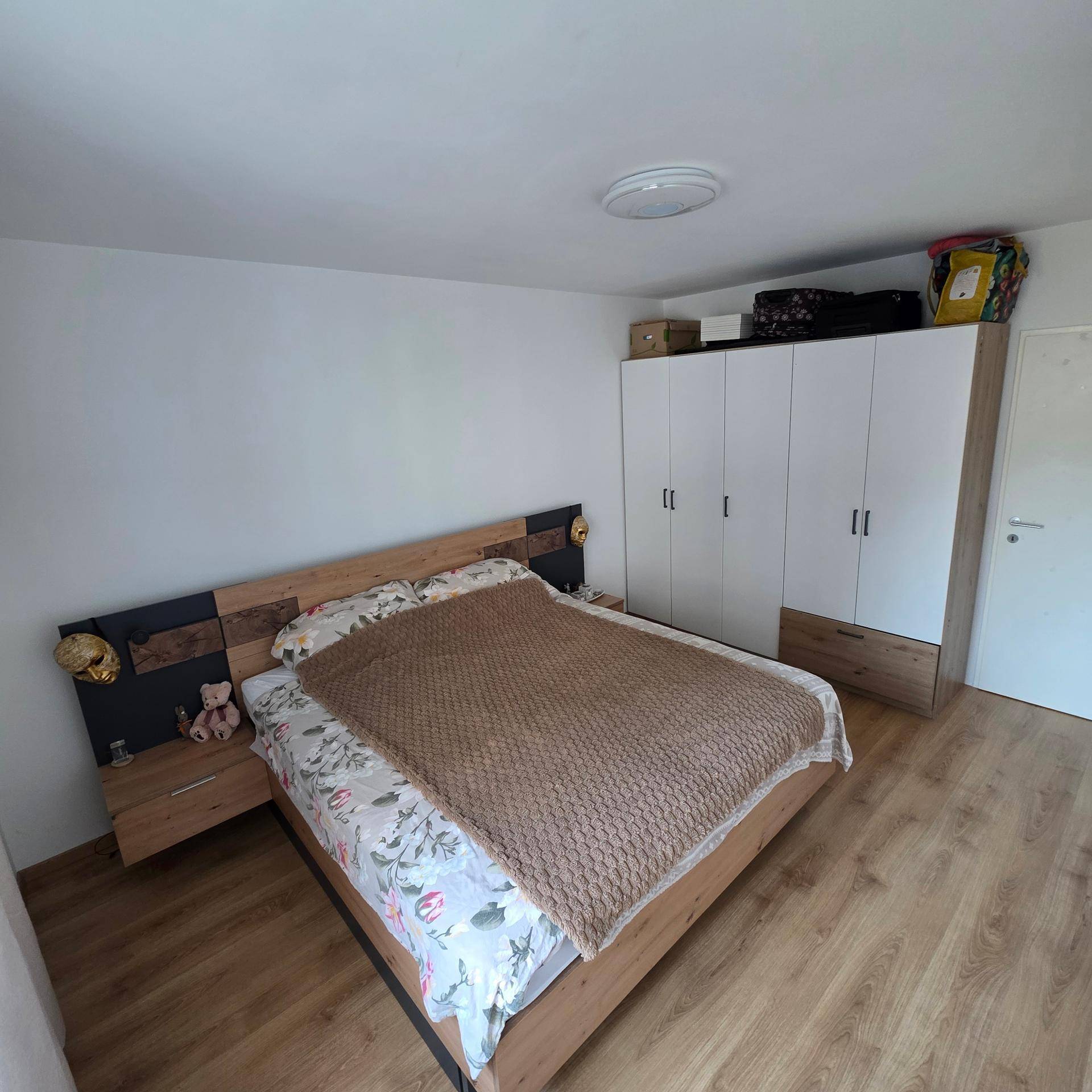 Schlafzimmer mit Doppelbett, Holzfußboden und großem Kleiderschrank.