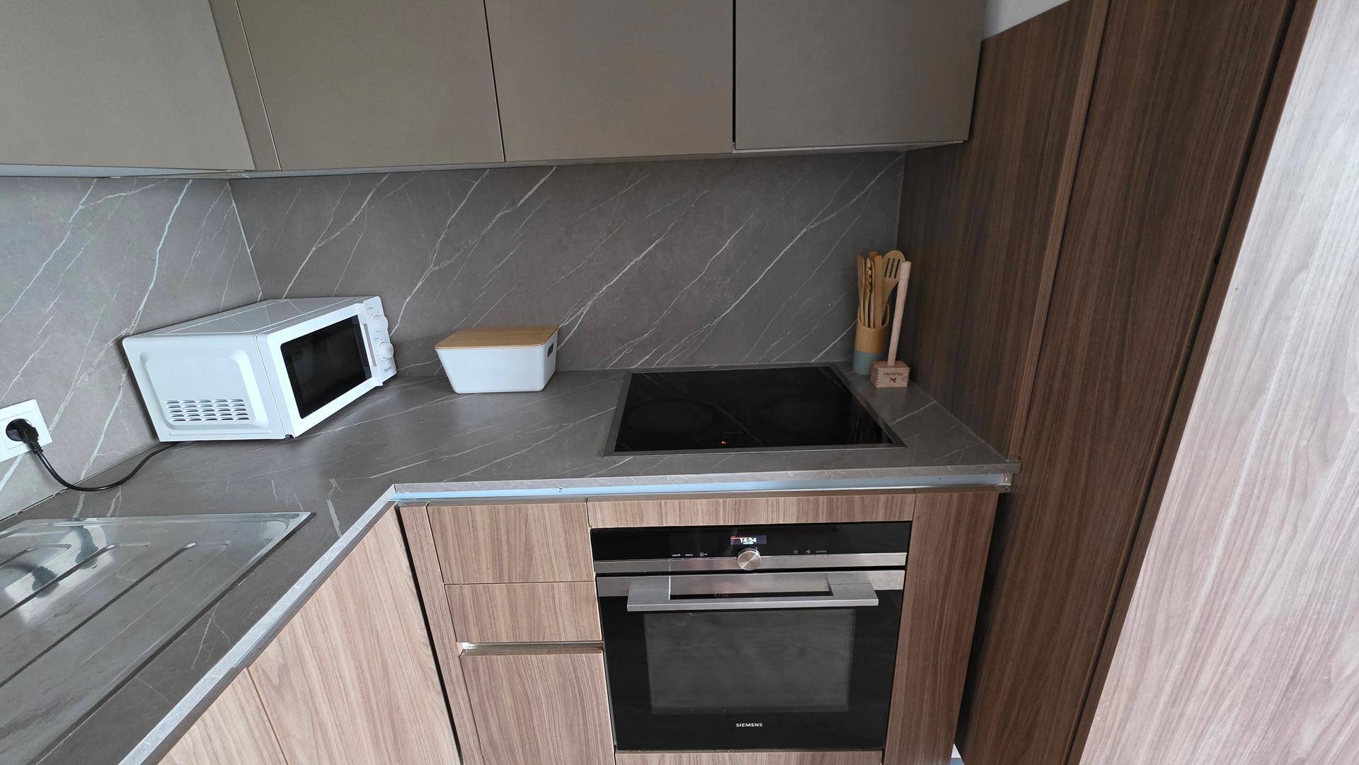 Detail der modernen Küche mit Induktionskochfeld, Backofen und Mikrowelle.