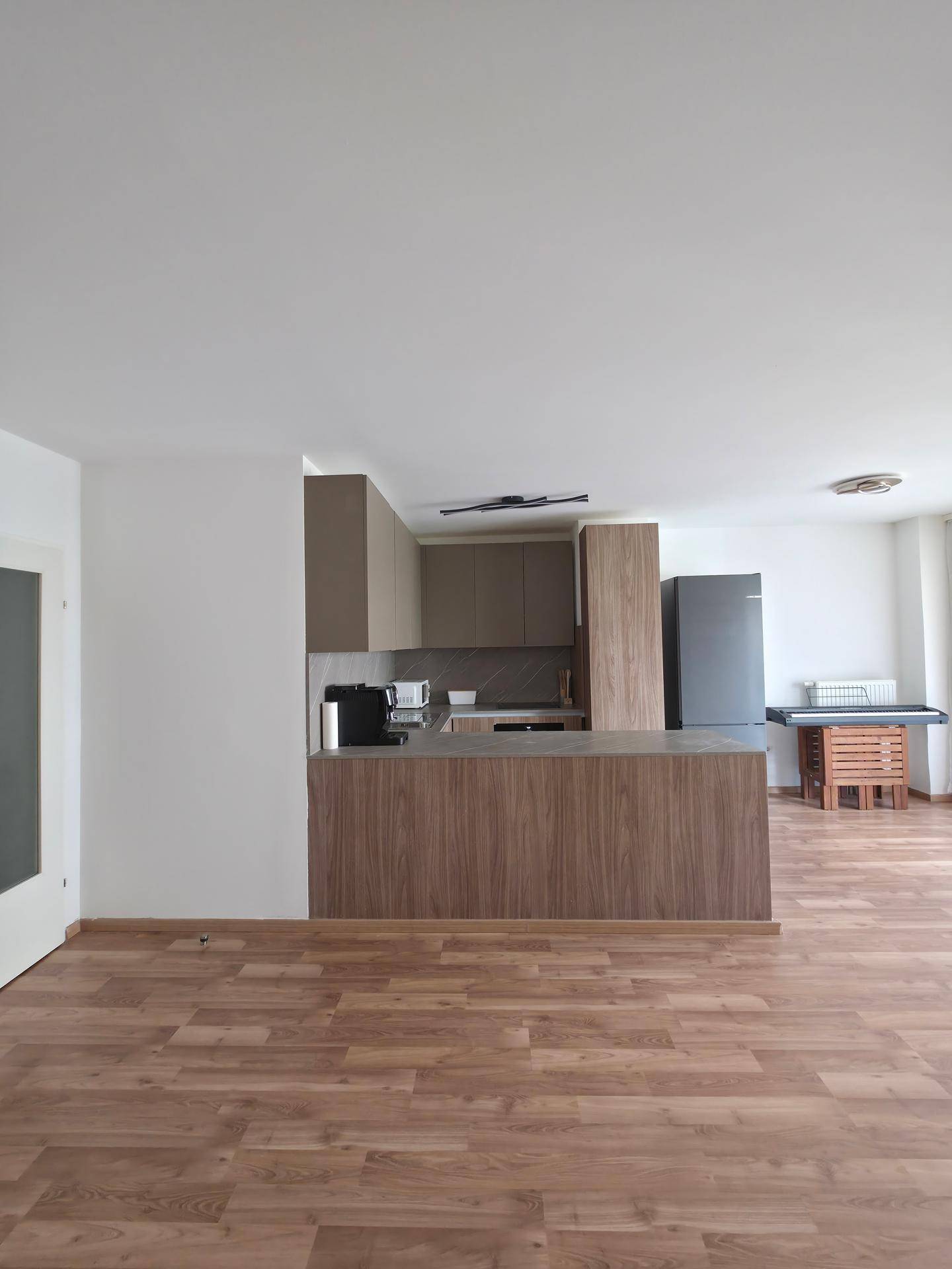 Moderne offene Küche mit Holzfronten, grauer Arbeitsplatte und integrierten Geräten.