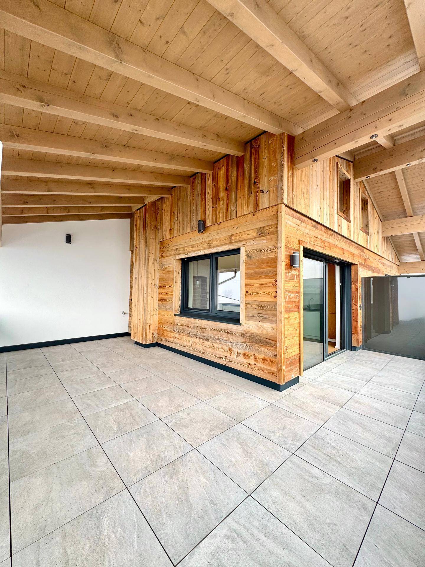 Geräumige Terrasse mit Fliesenboden und Holzverkleidung, ideal für entspannte Stunden im Freien.