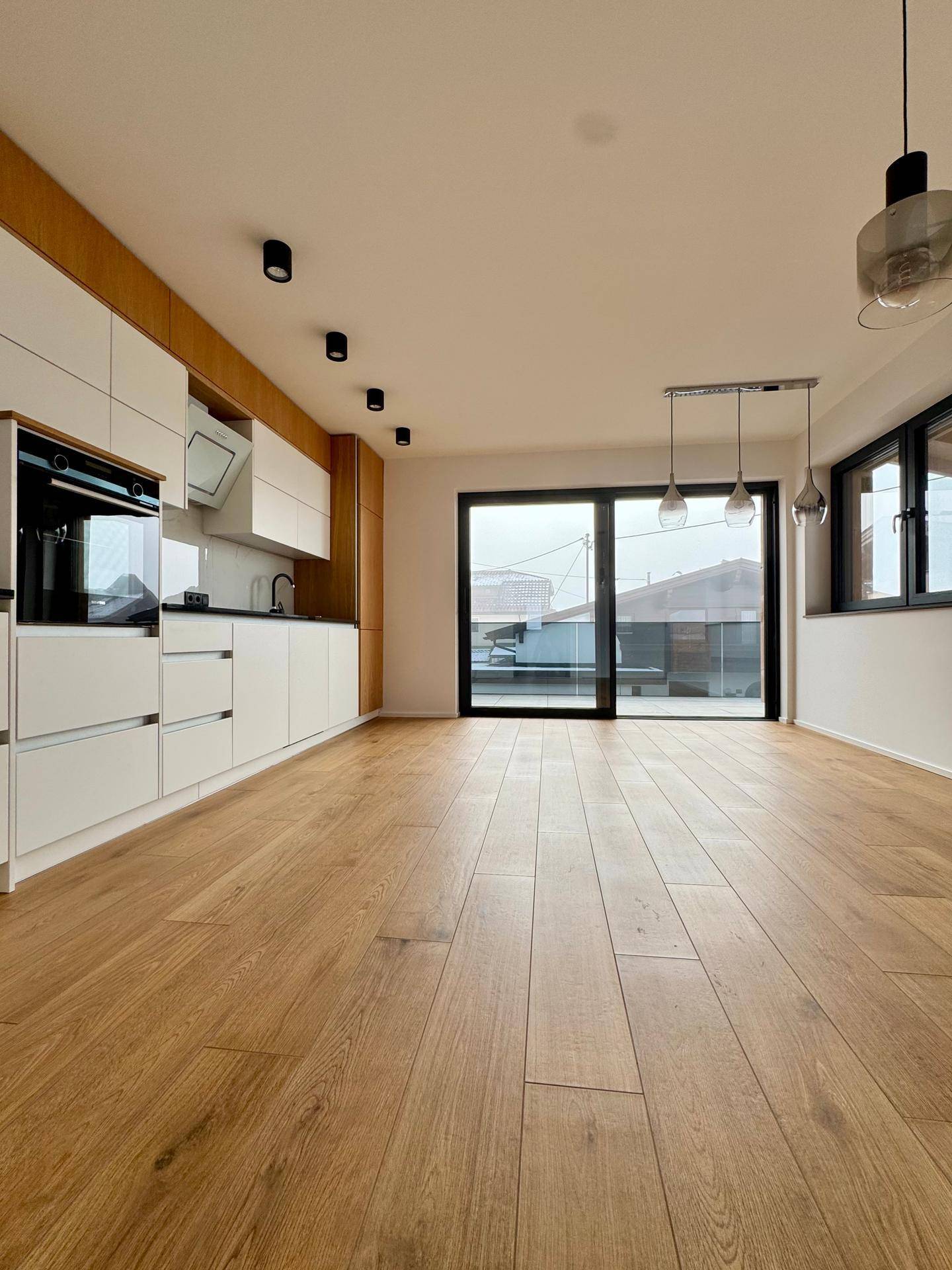 Moderne Einbauküche mit weißen und holzfarbenen Schränken sowie Zugang zur Terrasse.