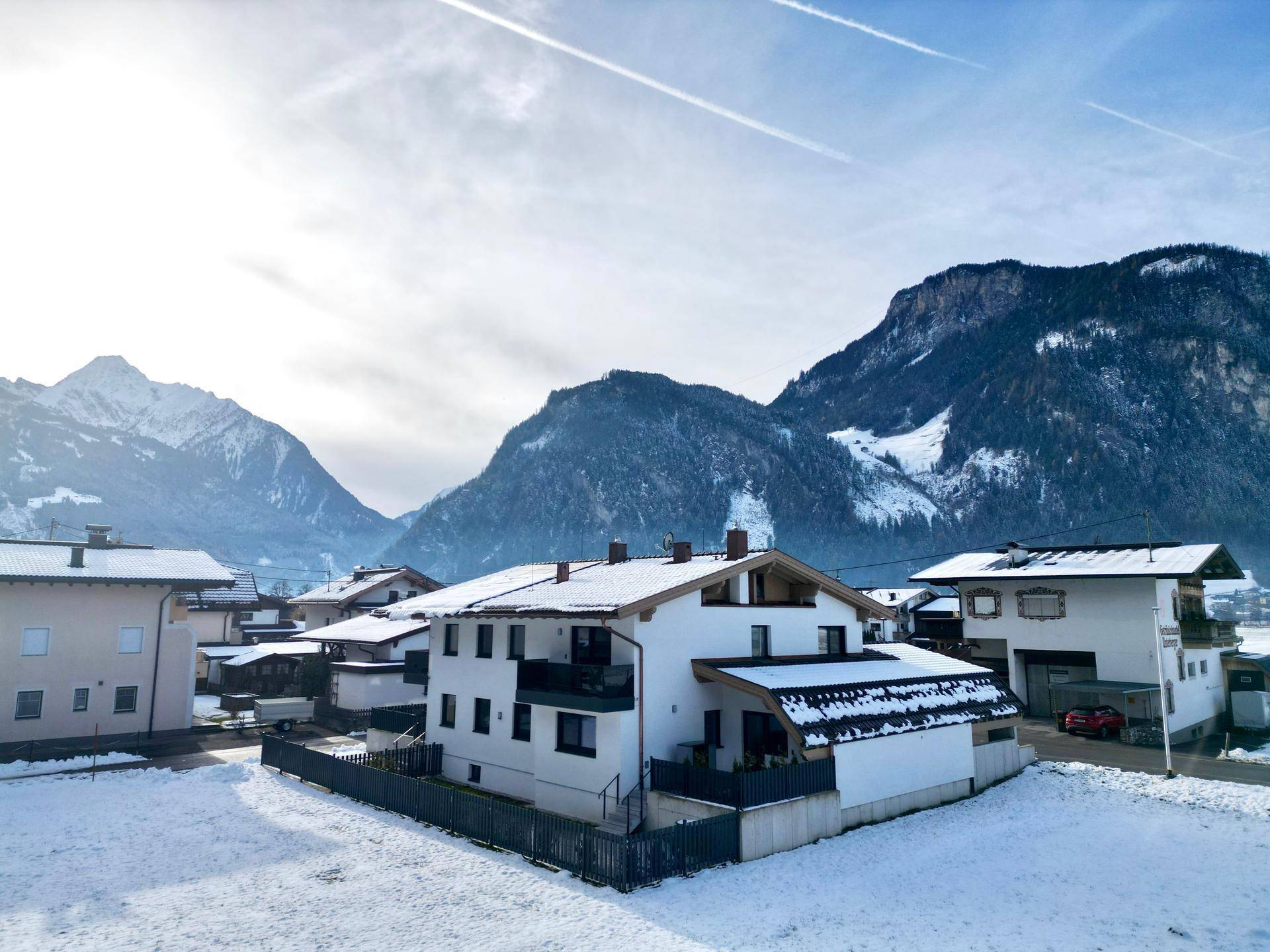 Winterliche Ansicht eines Hauses in einer verschneiten Berglandschaft mit klarem Himmel.