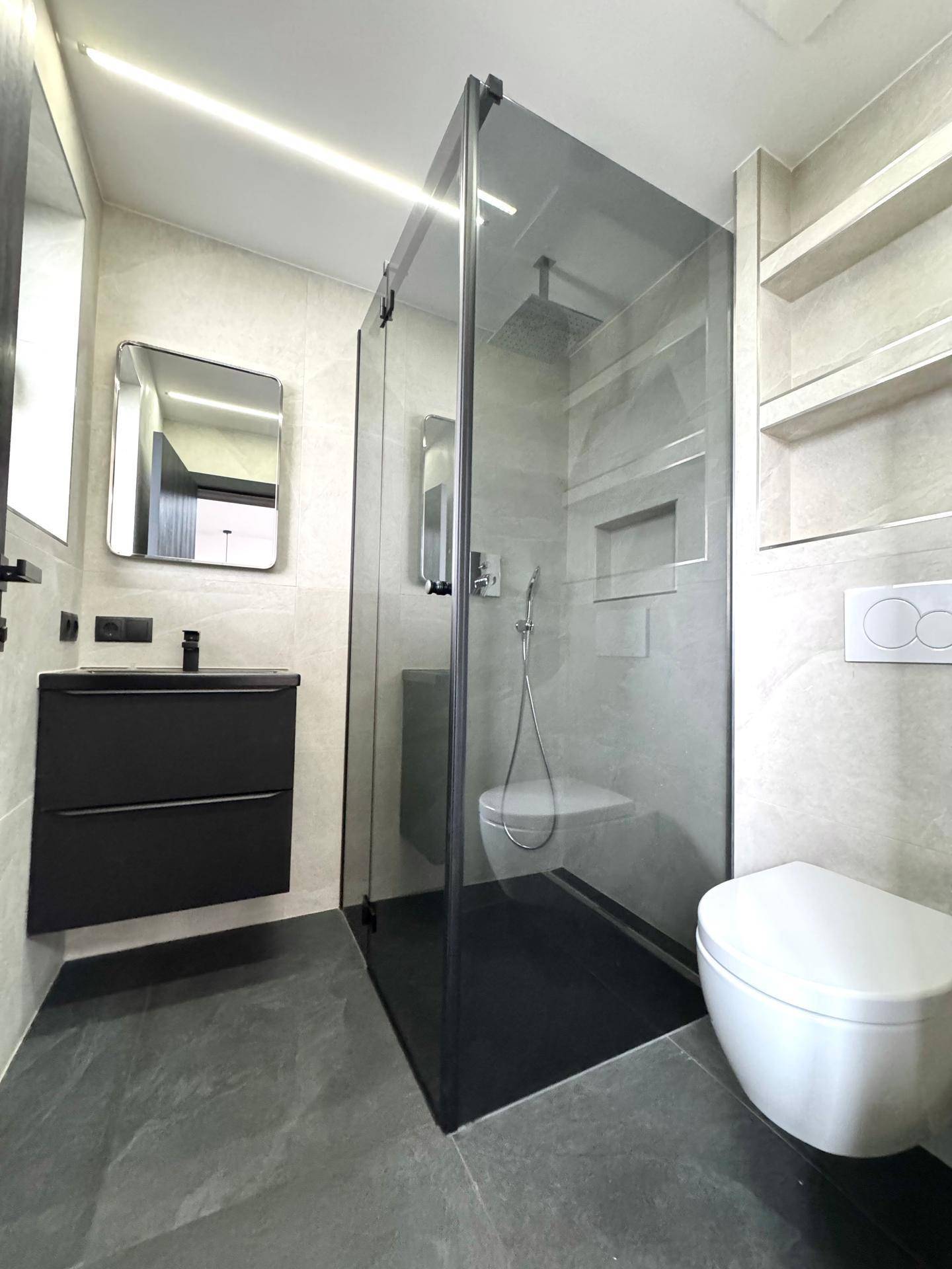 Modernes Badezimmer mit begehbarer Dusche, Wand-WC und eleganten grauen Fliesen.