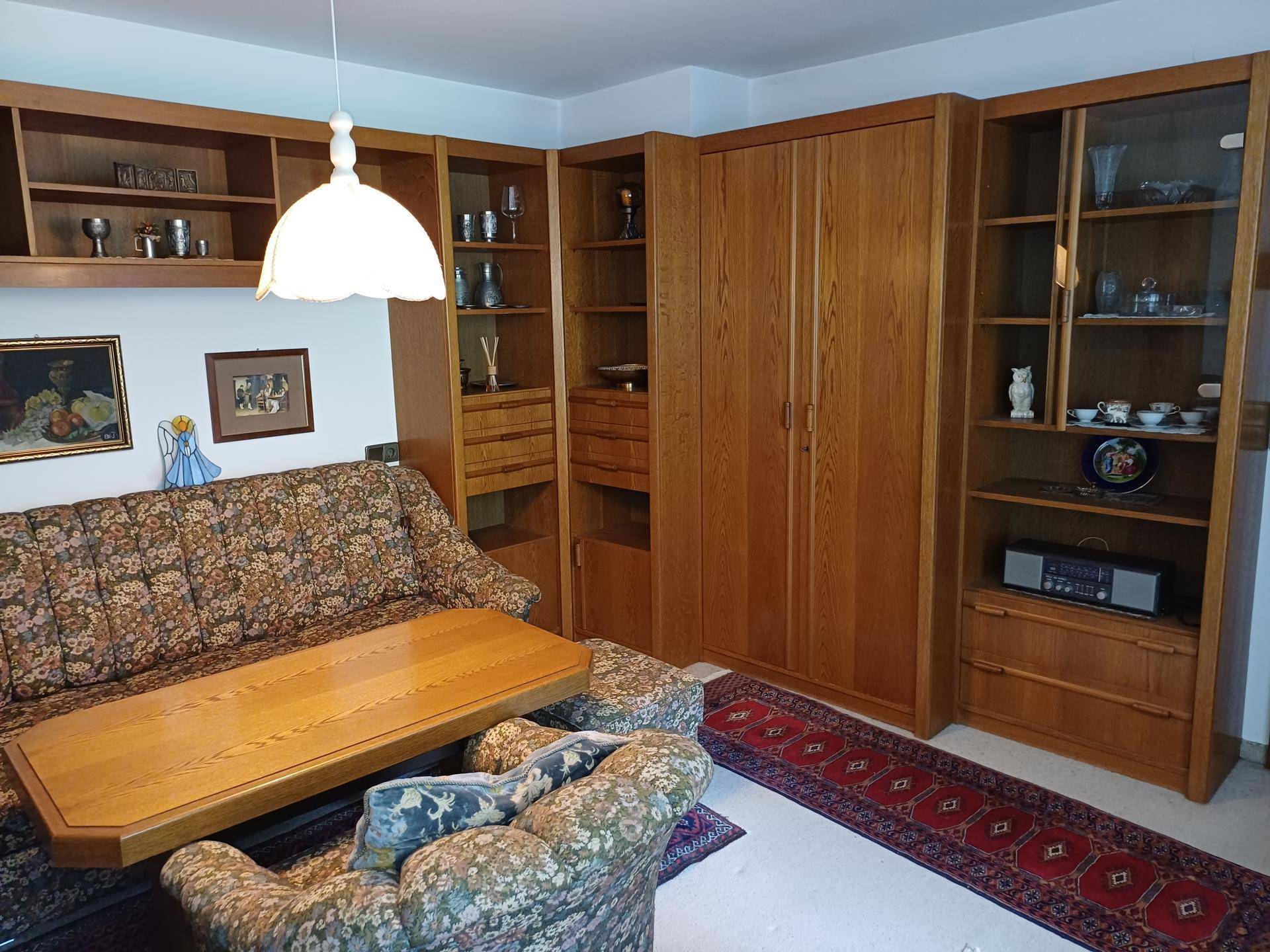 Wohnzimmer mit umfangreichen Holzregalen, Sofa und einem großen Teppich.