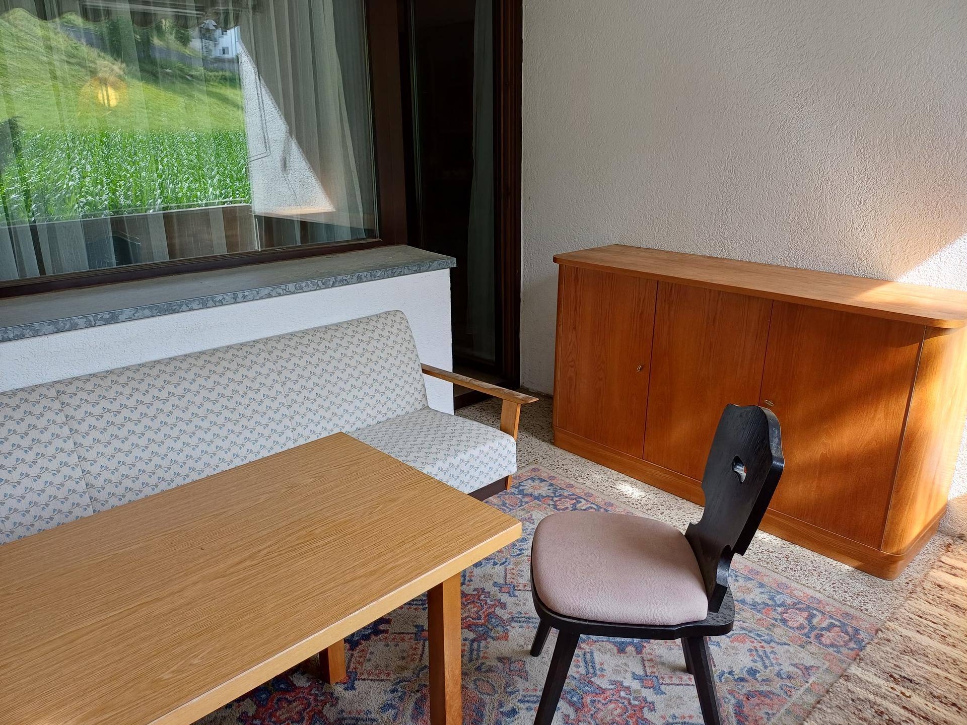 Balkon mit Sitzgelegenheiten und einem Holzschrank, ideal für entspannte Stunden im Freien.
