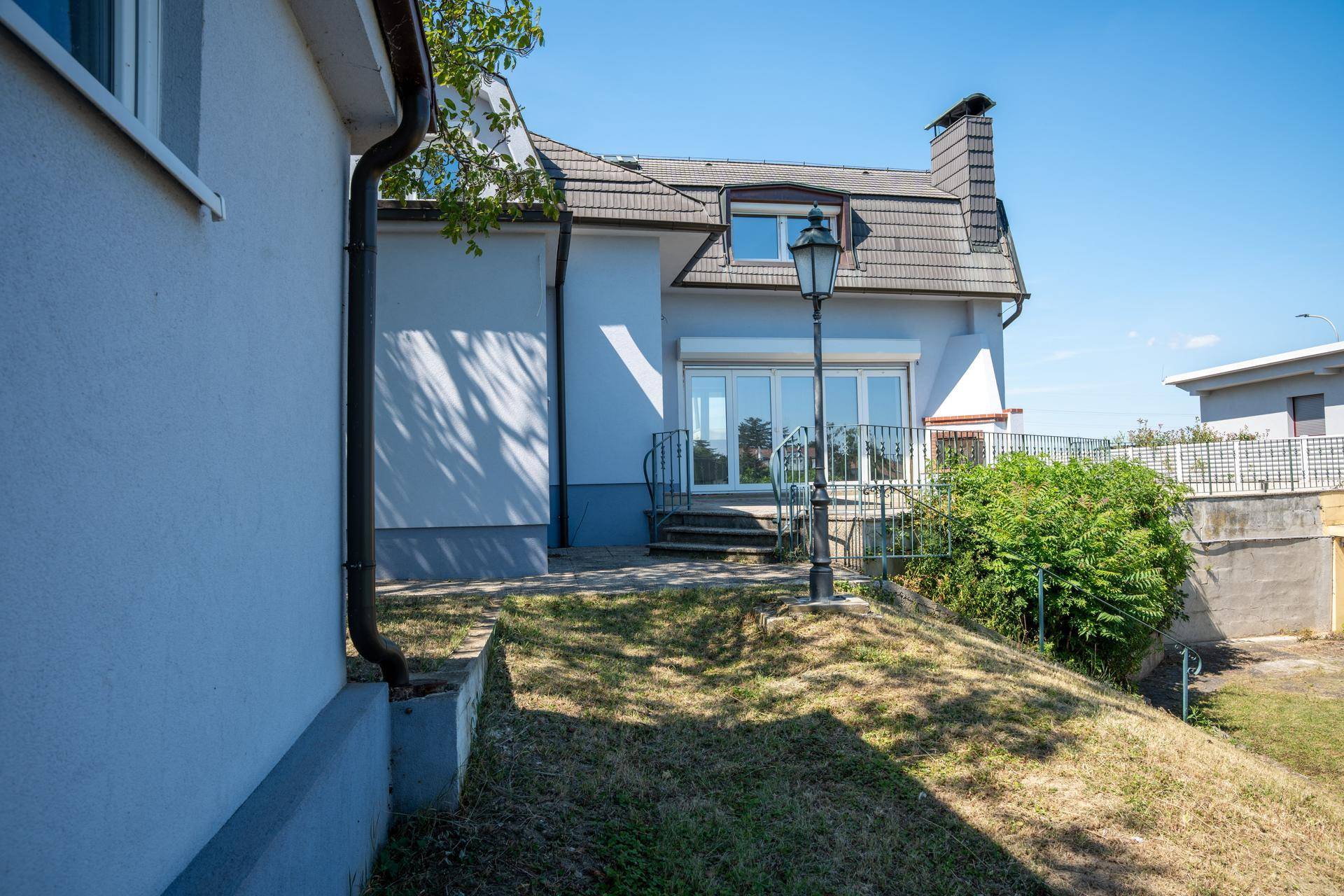 Rückseite des Hauses mit kleinem Gartenbereich und Zugang zur Terrasse.