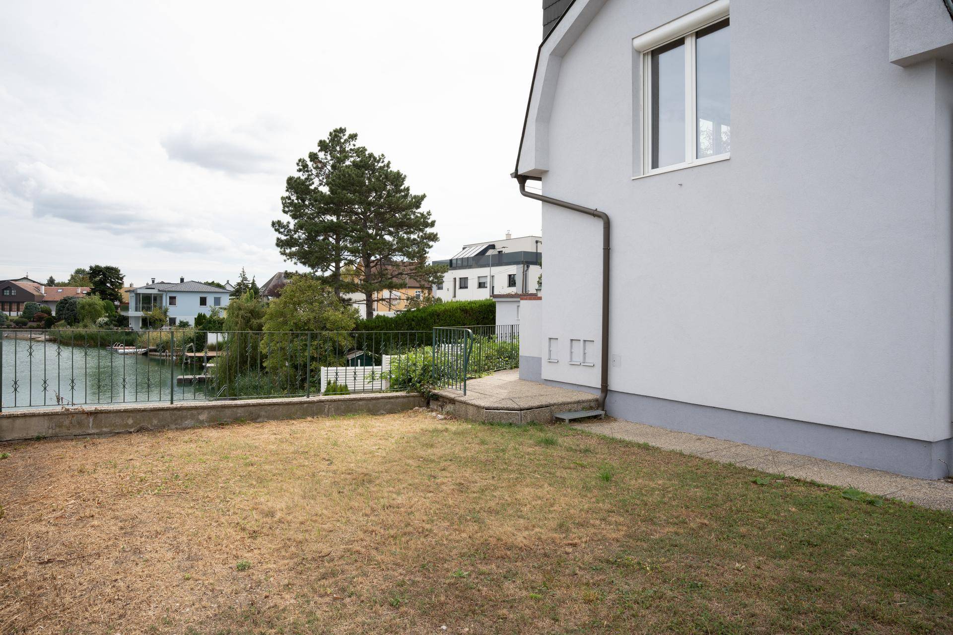 Gartenbereich neben dem Haus mit Rasenfläche und direktem Blick auf den See.