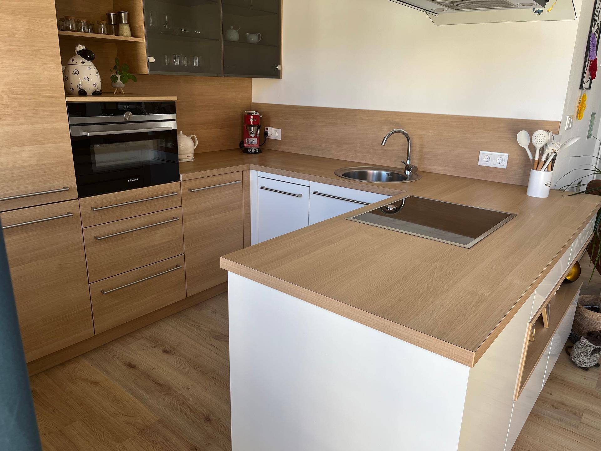 Moderne Einbauküche mit Holzfronten, weißer Arbeitsplatte und Induktionskochfeld.