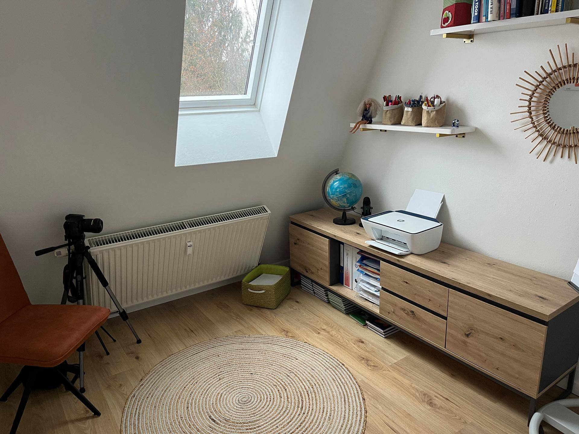 Helles Arbeitszimmer mit Holzboden, Schreibtisch und Dachfenster für viel Tageslicht.