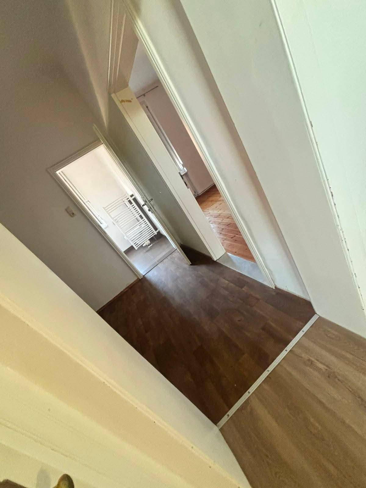 Flur mit Laminatboden und mehreren Türen, die zu den angrenzenden Räumen führen.