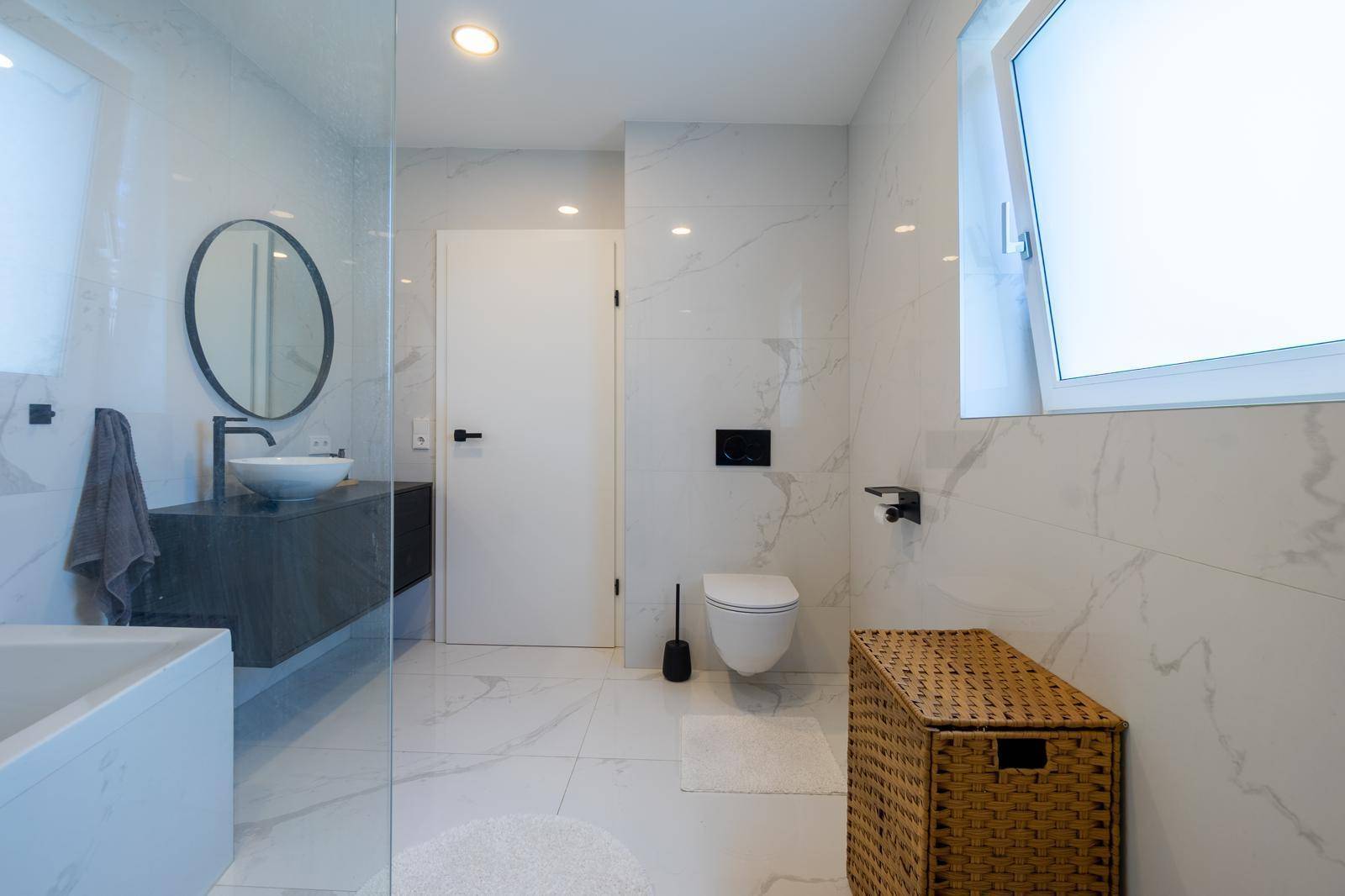 Modernes Badezimmer mit Marmorfliesen, Badewanne und begehbarer Dusche mit Glaswand.
