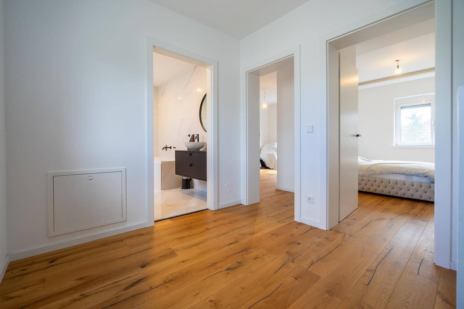 Flur im Obergeschoss mit Holzboden, der zu Schlafzimmer und Badezimmer führt.