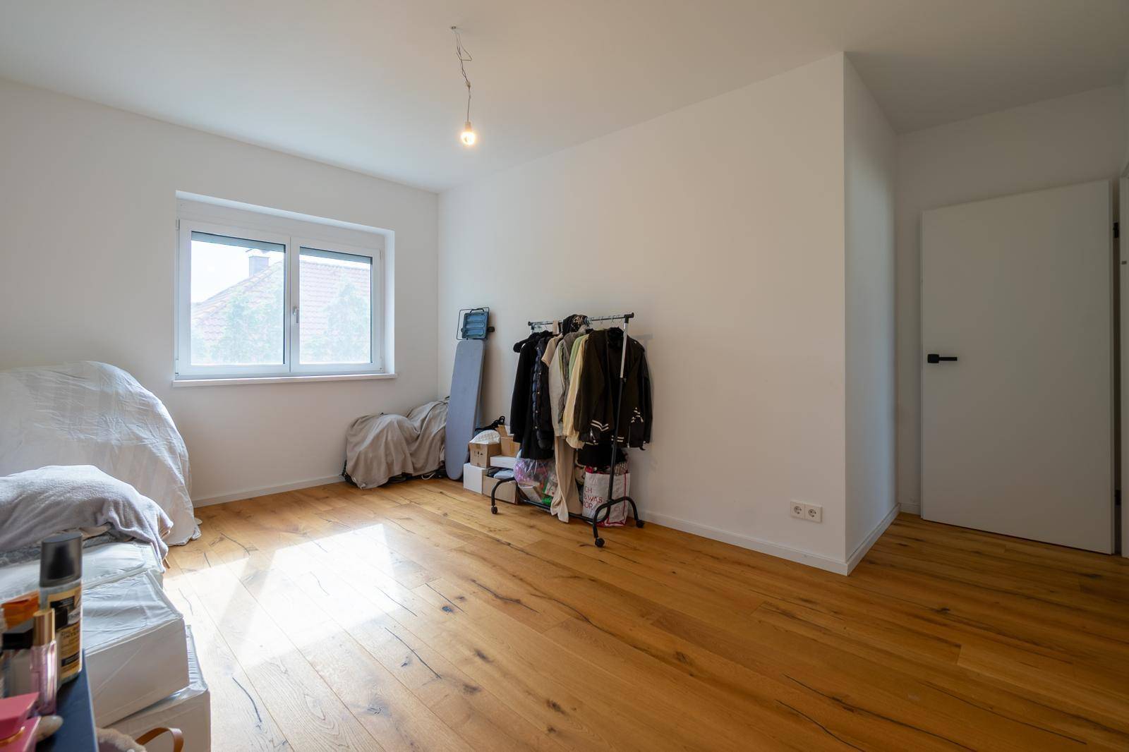 Geräumiges Schlafzimmer mit Holzboden, großem Fenster und viel Tageslicht.