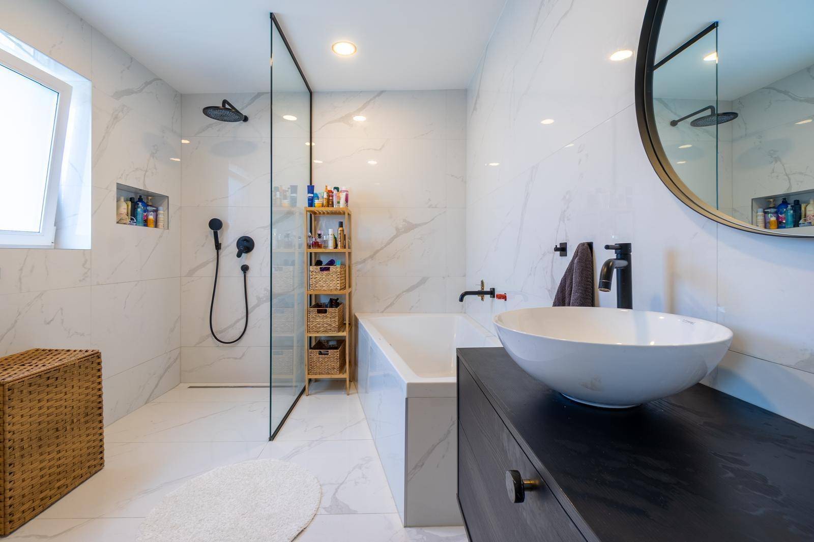 Elegantes Badezimmer mit Marmorfliesen, runden Spiegeln und modernen Armaturen.