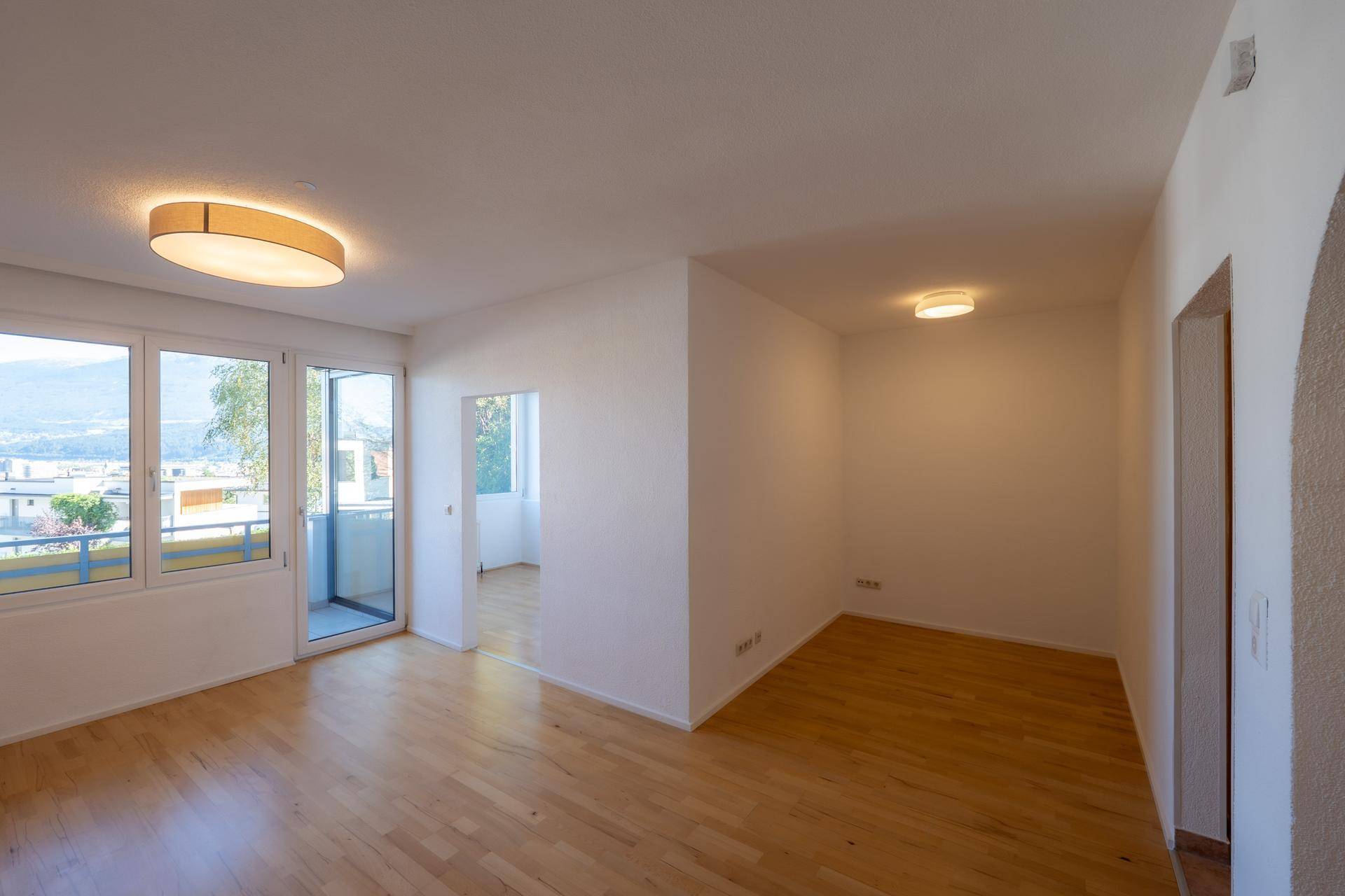 Geräumiger, heller Wohnbereich mit Holzboden und direktem Zugang zum Balkon.