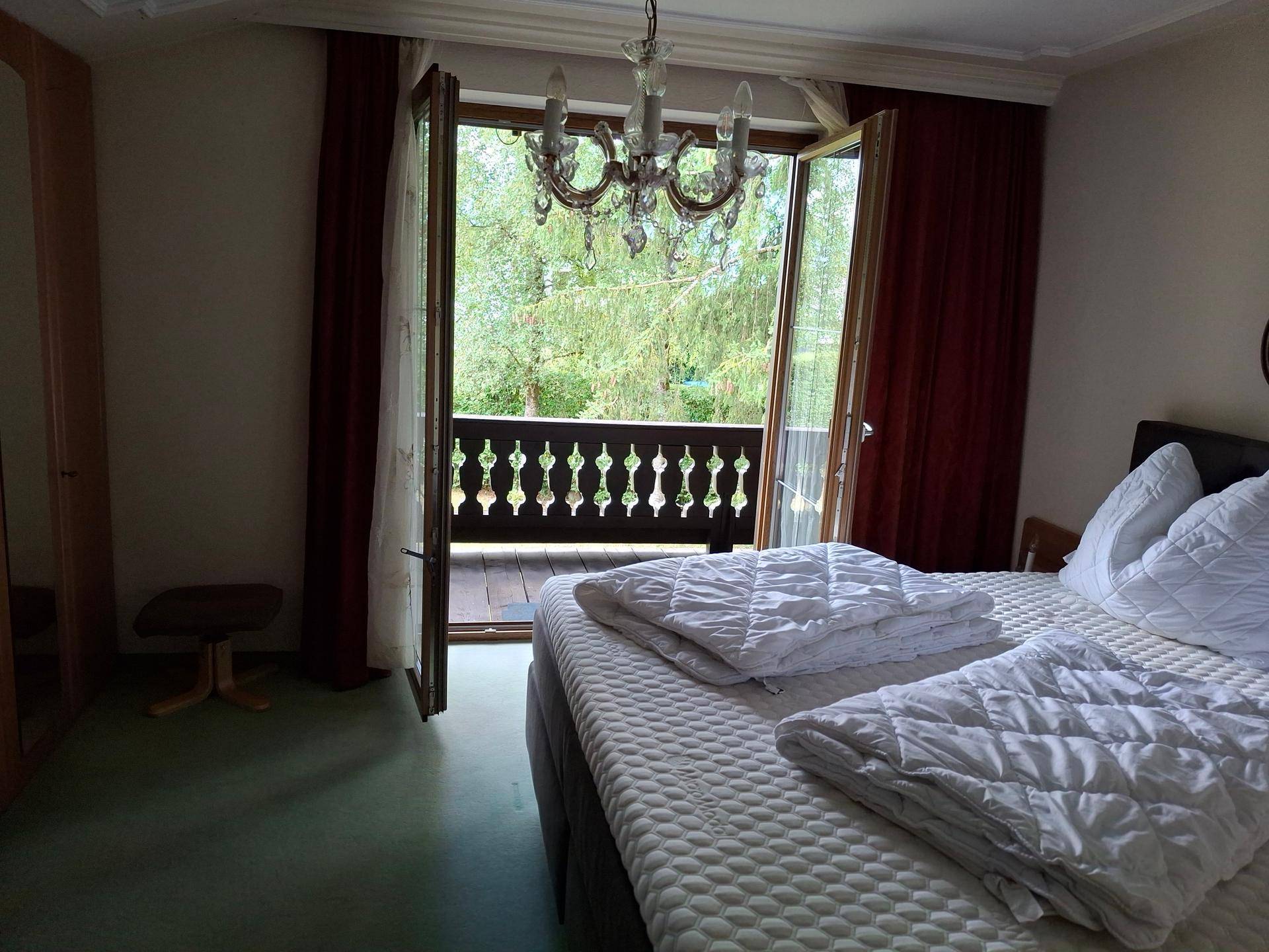 Helles Schlafzimmer mit Doppelbett, Kleiderschrank und direktem Zugang zum Balkon.
