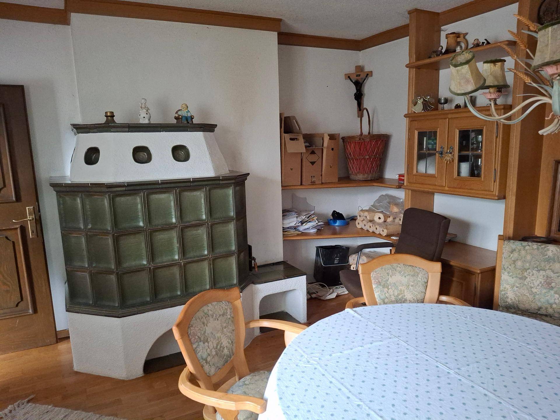 Gemütlicher Wohnbereich mit traditionellem Kachelofen, Holzelementen und rustikalen Möbeln.