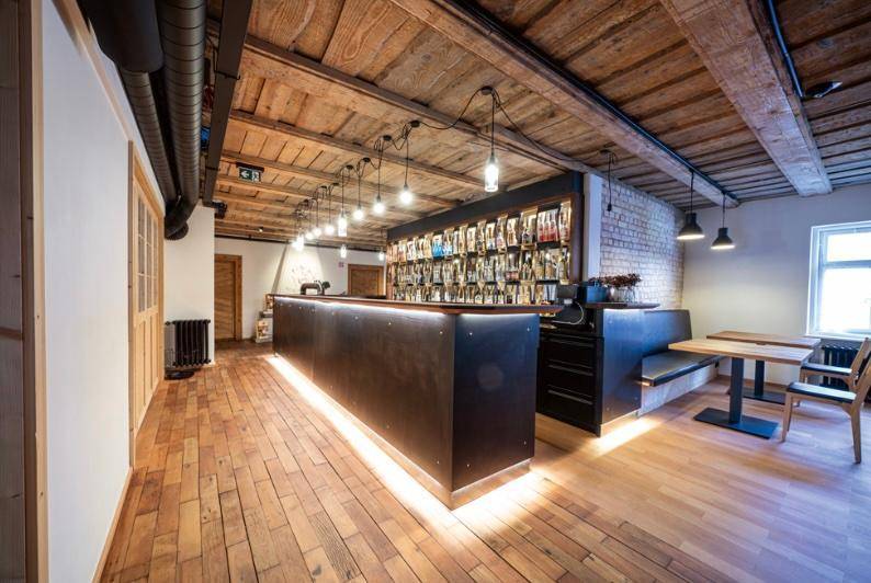 Moderne Bar mit Holzdecken, freiliegenden Rohren und indirekter Beleuchtung im Gastraum.