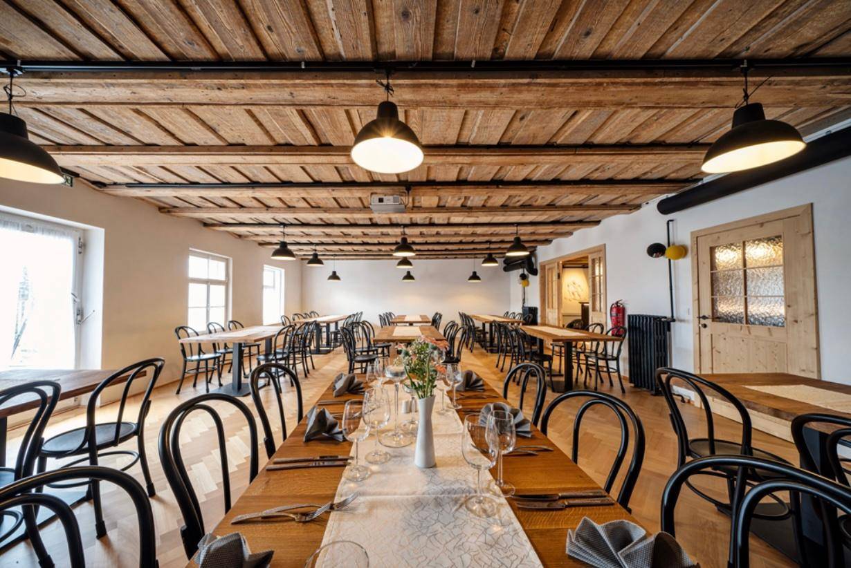 Großer Speisesaal mit Holzbalkendecke, Holzboden und vielen Tischen für Veranstaltungen.