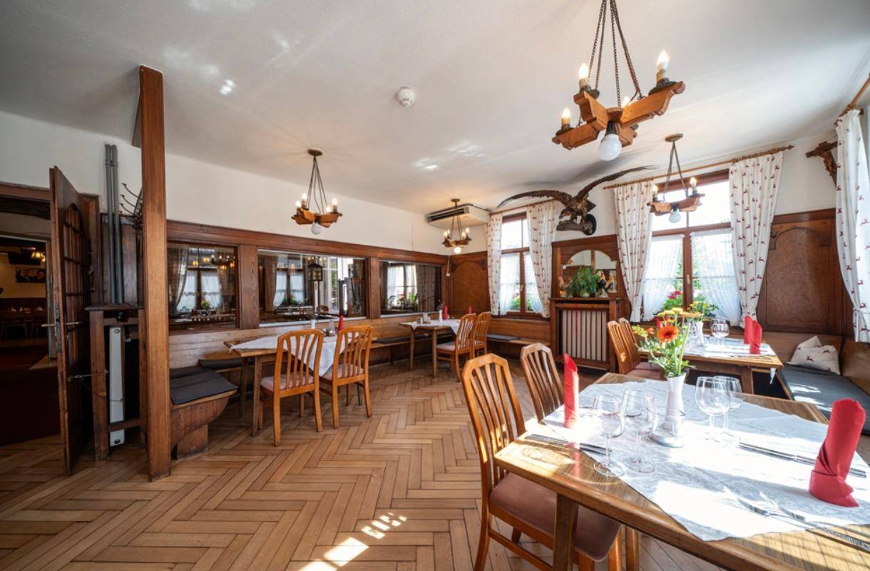 Gemütlicher Speisesaal mit Holzvertäfelung, Fischgrätparkett und traditionellen Kronleuchtern.