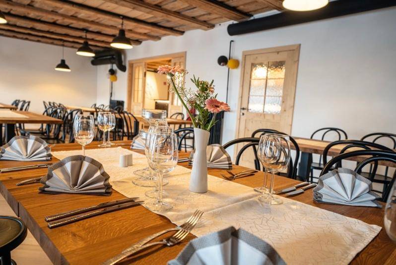 Festlich gedeckter Tisch in einem großen Speisesaal mit Holzboden und rustikaler Decke.