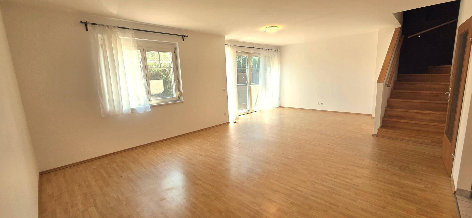 Helles Wohnzimmer mit Laminatboden und Zugang zur Terrasse oder zum Gartenbereich.