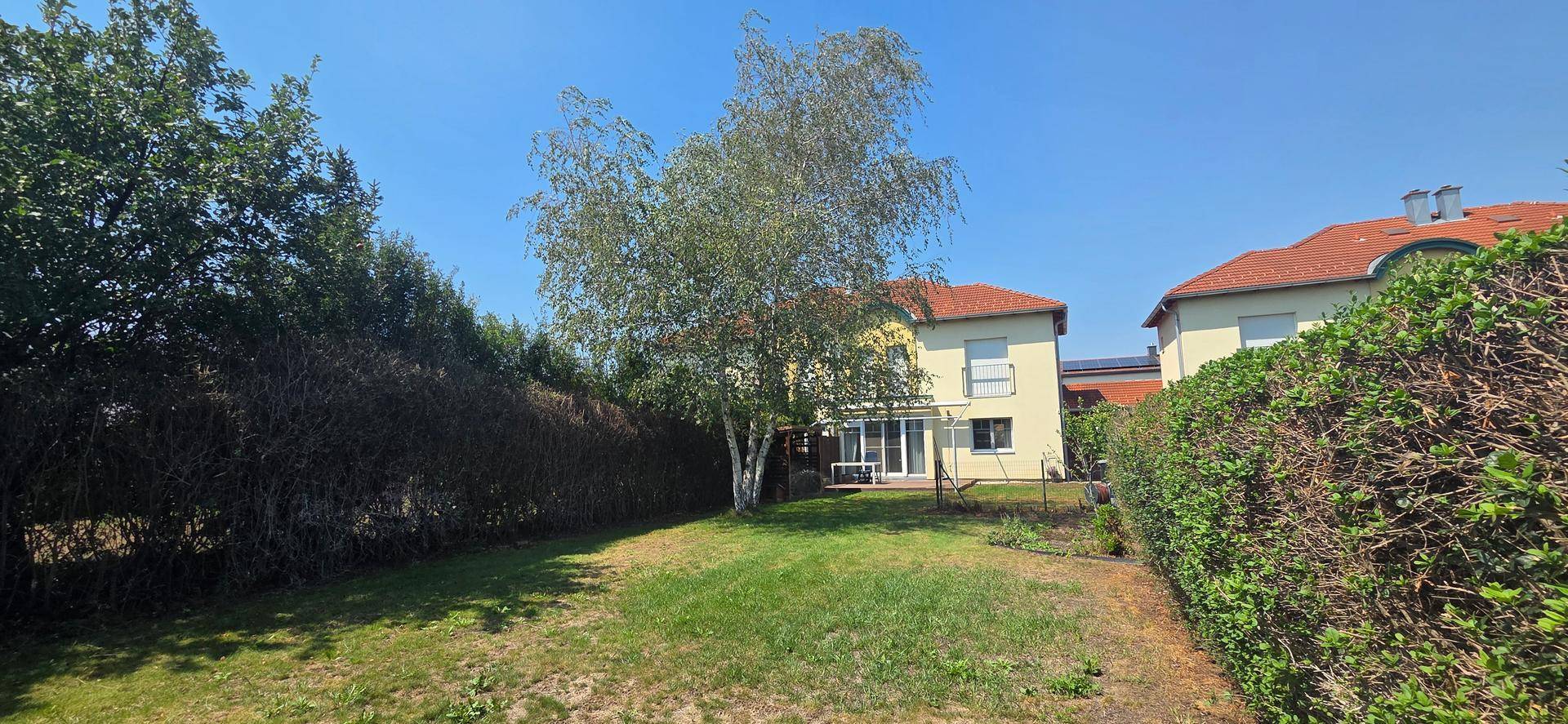 Großer, sonniger Garten mit Rasenfläche und hohen Hecken für Privatsphäre.